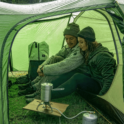Casal dentro da barraca, reforçando o conforto extremo e a vedação eficaz contra chuva, característica das barracas 4 estações.