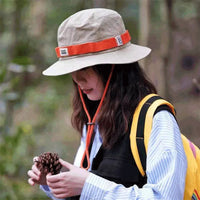 Usuária com o chapéu bucket em trilha, demonstrando a proteção solar no uso outdoor e a segurança da alça.