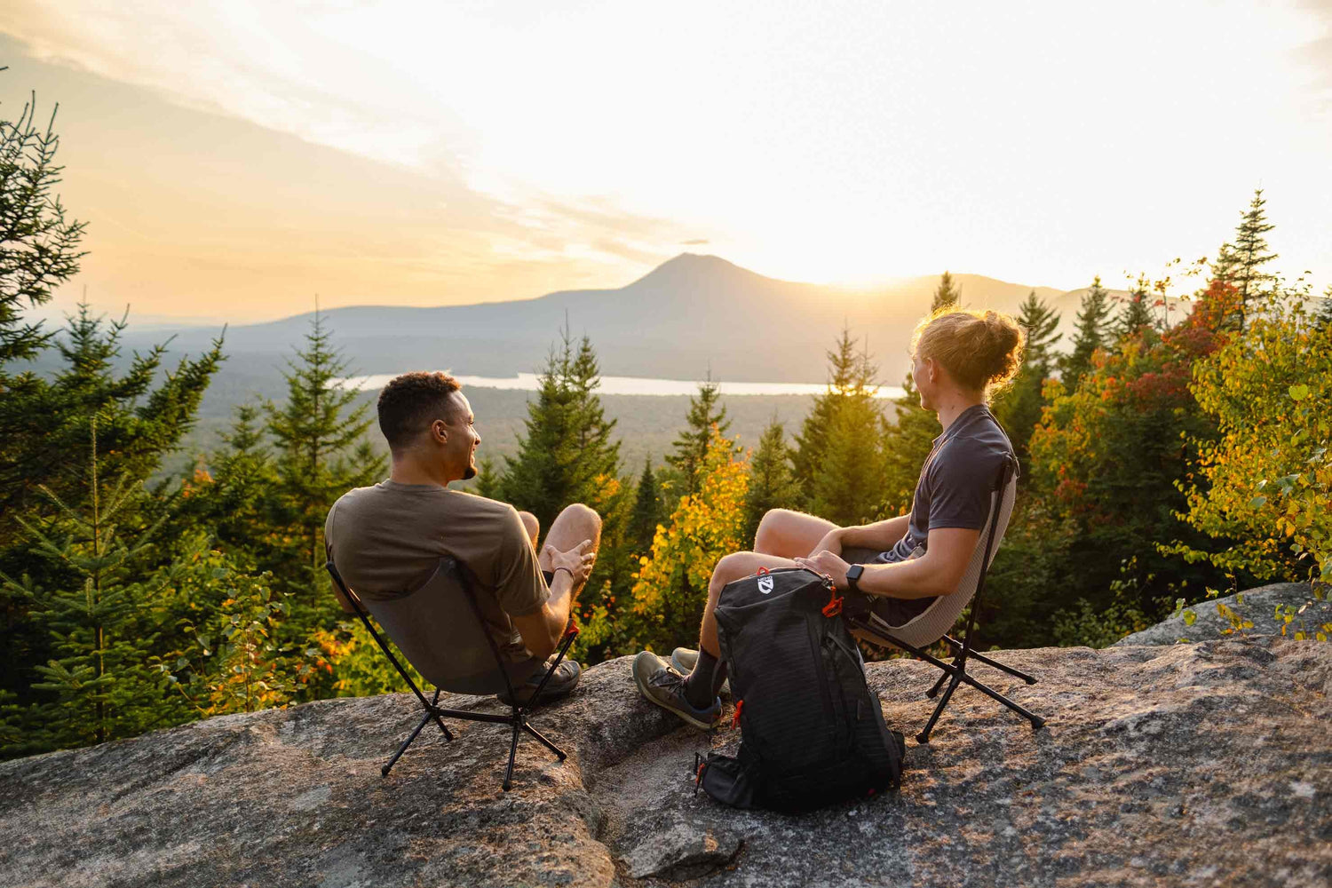 dois modelos na montanha usando suas cadeiras dobraveis da cultura puff em paisagem linda