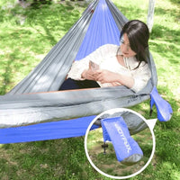 Usuária relaxando na rede Casal entre palmeiras na praia, promovendo conforto e relaxamento em ambiente premium outdoor.