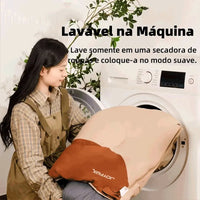 Saco de dormir sendo colocado na máquina de lavar, destacando o material lavável que garante higiene e durabilidade da fibra.